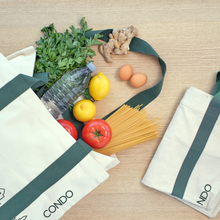 Load image into Gallery viewer, Reusable shopping bags with groceries including fruits, vegetables, and pasta on a wooden surface.
